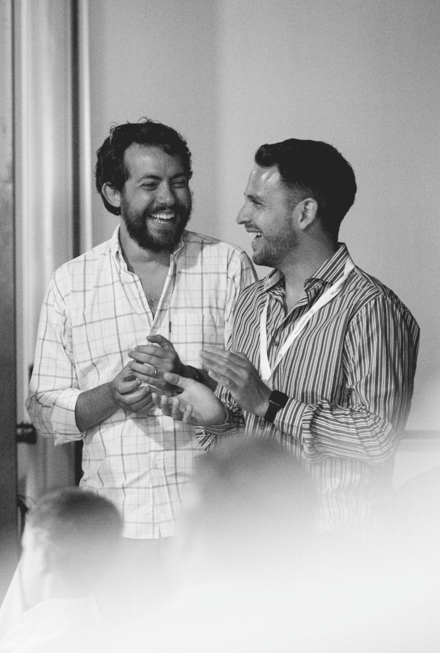 Julián Butti y Agustín Garassino, cofundadores de Syloper, riendo juntos en blanco y negro